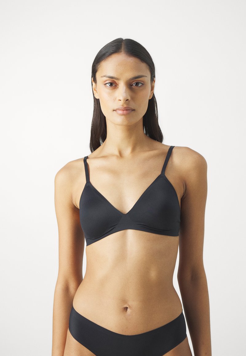 Black, seamless bralette with a V-neck design, thin adjustable straps, and a smooth texture. Designed for comfort and a minimalist style.