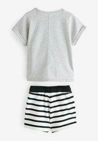 Grå T-shirt med kort ärm och bakstycke, kombinerad med vita shorts med svarta horisontella ränder och elastisk midja.
