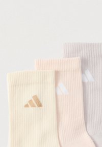 Τρία ζευγάρια ριμπ κάλτσες σε κρεμ, ροζ και γκρι, το καθένα με ένα μικρό λογότυπο σε αντίθετα χρώματα. Απαλό, βαμβακερό μείγμα υλικού.