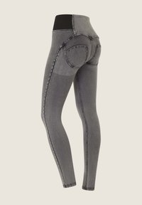 Tummanharmaat legginsit, joissa on korkea musta vyötärö, saumadetailit ja sileä pinta. Suunniteltu muotoilemaan istuvaa siluettia.