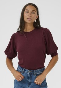 Burgundy tröja med ribbade, puffiga korta ärmar. Mjuk textur och rund halsringning, tillsammans med högmidjade denimshorts.