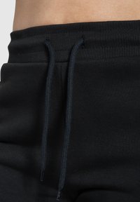 Zwarte sweatpants met een gestructureerde tailleband, voorzien van een koord in een bijpassende kleur en zachte stof voor comfort.