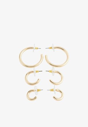 Boucles d'oreilles en ton or, présentant deux tailles avec une finition lisse et polie. Chaque boucle d'oreille a un fermoir à clou et un support en caoutchouc transparent.