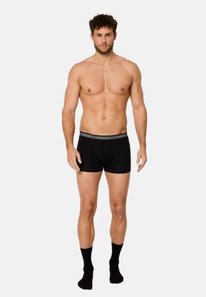 Musta pehmeästä kankaasta valmistetut bokserit, joissa on harmaa kuminauha vyötäröllä. Malli on istuva ja minimalistinen.