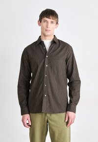 Braun gestreiftes Langarmhemd mit Button-Down-Kragen und Brusttasche, kombiniert mit hellgrünen Hosen. Glatte Stoffstruktur.