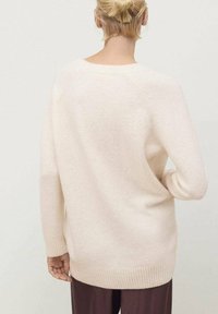 Hellrosa gestrickter Pullover mit lockerer Passform, gerippten Bündchen und Saum, weicher Textur und Raglanärmel-Design, von hinten betrachtet.