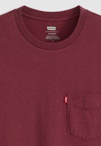 Burgunderfarbene Rundhals-T-Shirts aus Baumwollmischung mit einer linken Brusttasche und einem kleinen roten Levi's-Label. Weiche, glatte Textur.