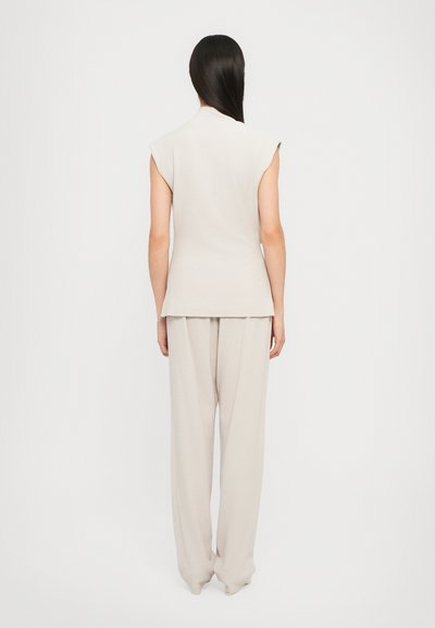 Beige ärmelloses Oberteil und passende lockere Hose, aus weichem, leichtem Stoff mit glatter Textur, in geradem Schnitt.