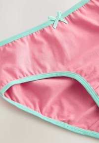 Roze zwembroek met mintgroene afwerking en strikdetail. Zachte, gladde stof met een strakke pasvorm en elastische tailleband.