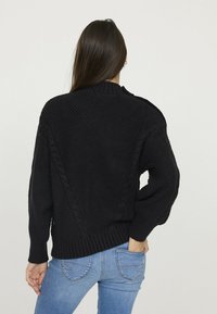 Pull noir en tricot avec un motif texturé, des poignets côtelés et un col rond. Présente un design en tricot à torsades le long du dos.