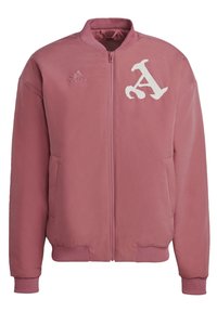 Rosa bomberjacka i ett slätt material. Har en vit broderad bokstav "A" och en Adidas-logotyp på vänster bröst. Dragkedja fram, ribbade muddar.
