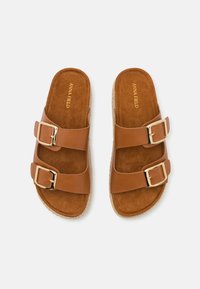 Sandalias de verano marrones con dos correas ajustables, que cuentan con hebillas doradas. Plantilla de ante y suela de corcho texturizada para mayor agarre y comodidad.