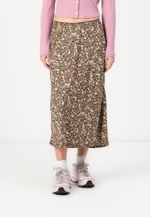 Floral midi skirt with a black background, featuring multicolored flowers. Worn with light pink sneakers and white socks.