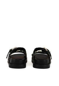 Sorte sandaler med justerbare stropper, en tyk solet, og et tekstureret blomstermønster. Har en metalspænde til lukning. Flad og åbent bagdesign.