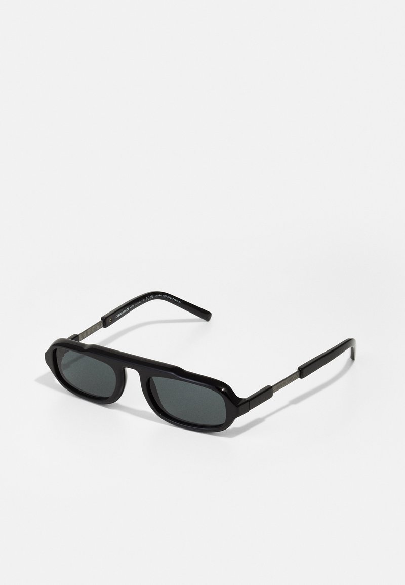 Schwarze Sonnenbrille mit kantigen Rahmen, dunklen Gläsern und metallischen Bügeln mit eingravierten Details. Glattes, glänzendes Finish mit einem auffälligen Design.