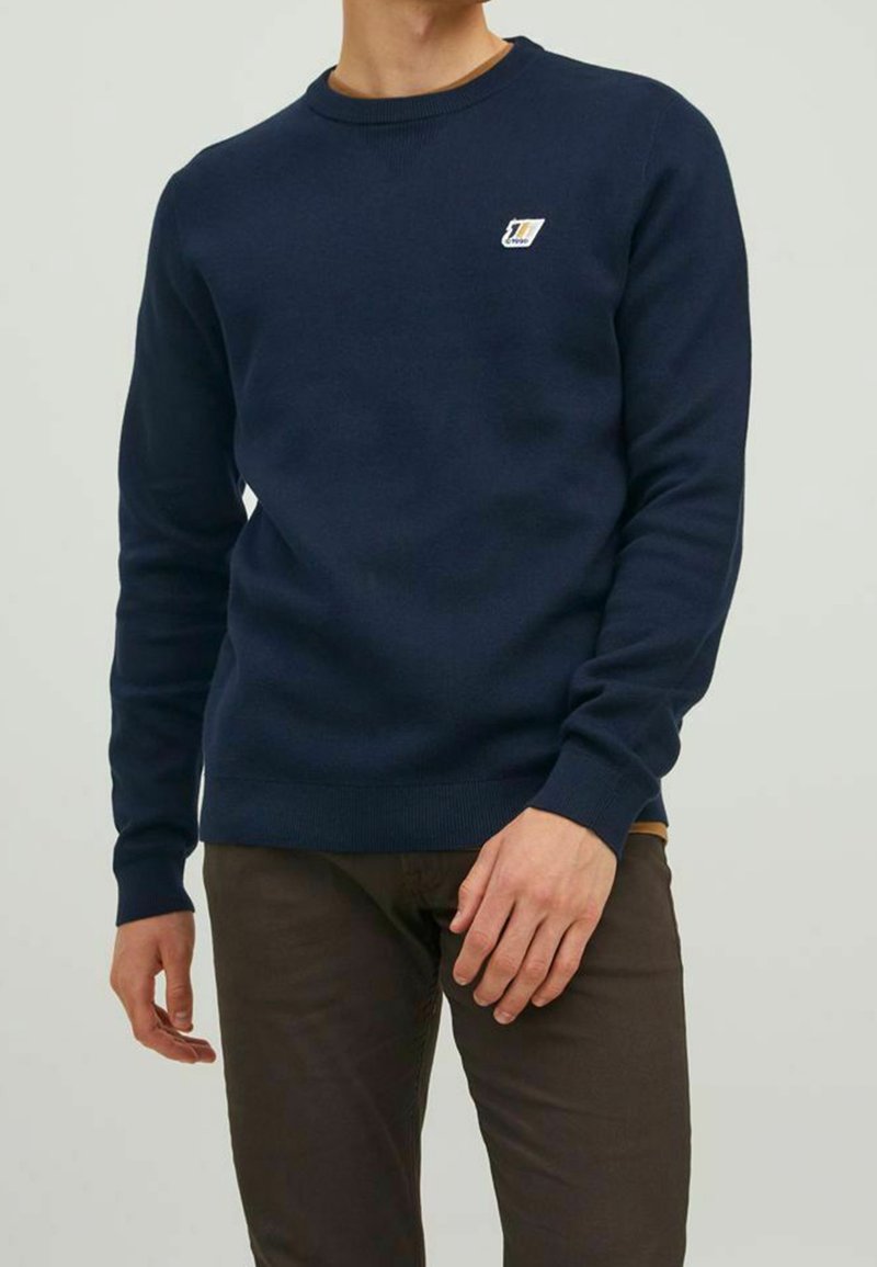 Schnitt aus marineblauem Strickstoff mit langen Ärmeln, rundem Halsausschnitt, gerippten Bündchen und Saum. Mit kleinem Logo auf der Brust.