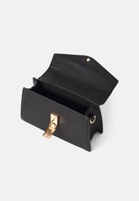 Pochette rectangulaire en cuir noir avec rabat ouvert, fermoir doré et détail anneau sur le côté, présentée sur fond blanc.