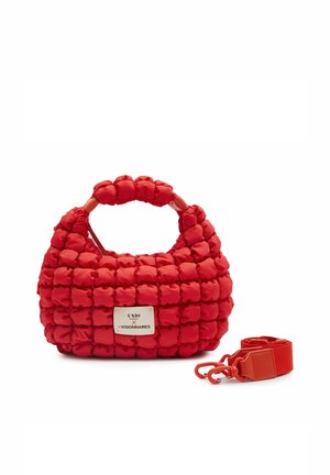 Rote gesteppte Handtasche mit Obergriff und abnehmbarem Schultergurt, vorne mit einem weißen Etikett mit schwarzem Text.