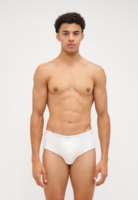 Slip in cotone bianco con una cintura elastica morbida recante il logo "GAP". Design semplice e aderente senza motivi.