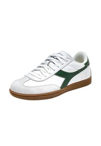 Witte sneaker met groene accenten, van suède en leer, ronde neus, vetersluiting, en rubberen zool met een gestructureerd patroon.