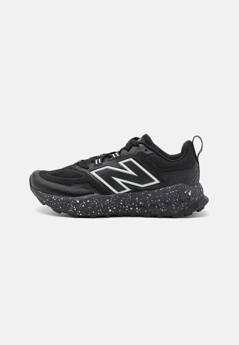 Chaussure de sport noire avec une tige texturée, des accents réfléchissants et une semelle intermédiaire mouchetée en noir et blanc. Semelle extérieure en caoutchouc pour l'adhérence.