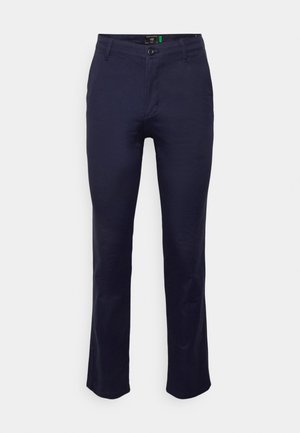 Pantaloni drept, de culoare albastru marin, din bumbac cu o textură netedă. Au o închidere cu nasture și buzunare atât în față, cât și în spate.