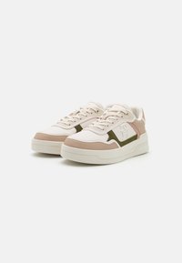 Zapatillas deportivas con un upper blanco, acentos en beige claro y detalles en verde oliva y rosa. Presentan paneles texturizados y suelas gruesas y blancas.