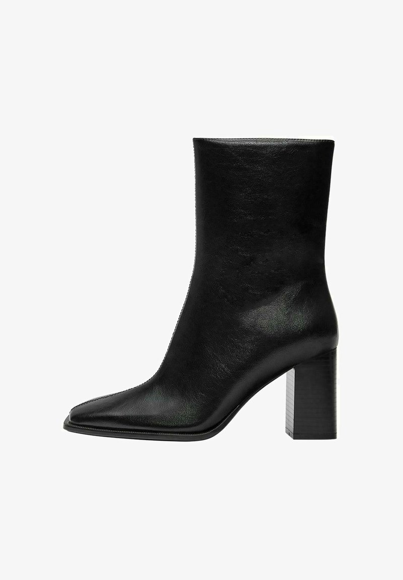 Crne gležnjače od glatke kože, sa šiljastim prstom i masivnom pravokutnom petom. Minimalistički dizajn bez ukrasa.