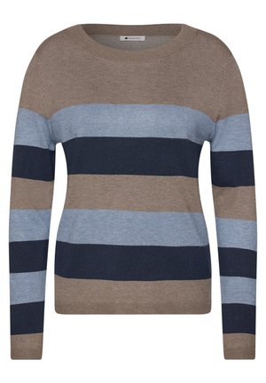 Femme aux cheveux bruns mi-longs sourit doucement, portant un pull en laine rayé marron, bleu clair et bleu foncé sur un fond uni.