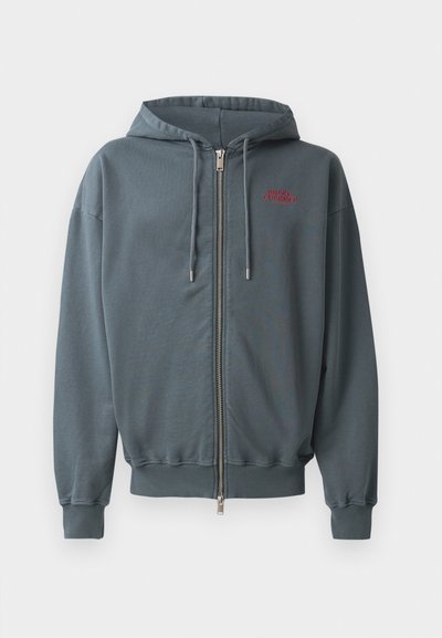 Sweat-shirt zippé à capuche en mélange de coton gris foncé, avec des poignets et un bas côtelés, arborant un petit motif en texte rouge sur le côté supérieur gauche de la poitrine.