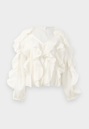 Hvit bluse laget av lett stoff med fremtredende volangdetaljer, V-hals og lange puffede ermer med knappeåpning.
