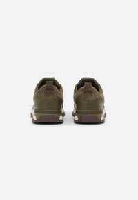 Grüne Wildledersneaker mit strukturierter Oberfläche, verstärktem Fersenbereich und beigen Gummisohlen. Inklusive einer Schlaufe an der Rückseite für einfaches An- und Ausziehen.