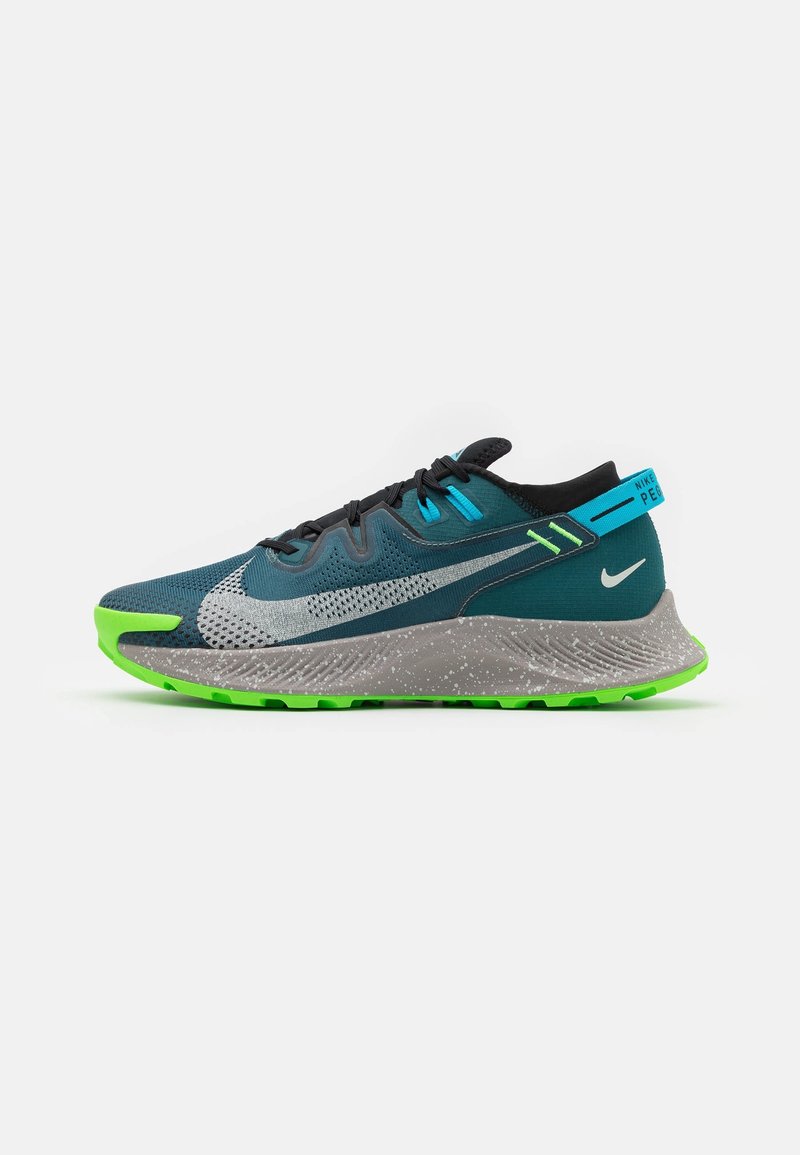 Chaussure de sport en maille teal avec des accents argentés, des lacets noirs et une semelle intermédiaire grise mouchetée ; présente une semelle brillante verte et des détails bleus.