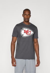 Grå bomulds-t-shirt med et stort hvidt og r�ødt Kansas City Chiefs-logo i en stiliseret form på forsiden. Korte ærmer, rund halsudskæring.
