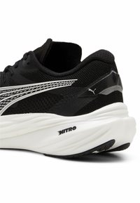 Black athletic shoe with mesh upper, white accents, and textured sole. Features "NITRO" branding on the heel and sleek design.