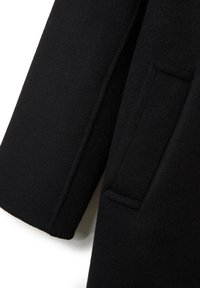 Cappotto di lana nera con una texture liscia, colletto a punta e una tasca laterale singola all'orlo. Linee pulite e silhouette strutturata.