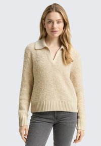 Kremowy sweter typu pulower wykonany z teksturowanego materiału, z kołnierzykiem oraz ściągaczami przy rękawach i u dołu.