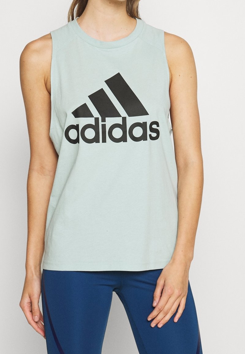 Canotta di cotone azzurro chiaro senza maniche con grande logo Adidas nero sul petto. Texture liscia e scollo rotondo.