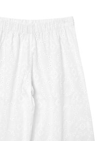 Weiße bestickte Hosen aus einem weichen, strukturierten Stoff, mit floralen Mustern und Ösen-Details entlang des Bundes und der Beine.