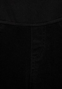 Jeans in denim nero con una texture liscia, dotati di vita e dettagli sulle tasche laterali, tutto in un colore nero uniforme.