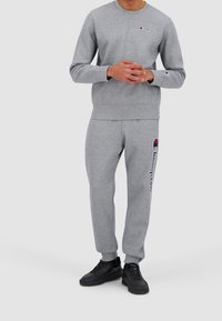 Šedá bavlněná mikina a kalhoty set s žebrovanými manžety a pasem. Obsahuje malé logo značky na hrudi a boční logo na kalhotách.