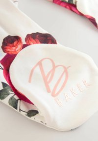 Skarpety w kwiatowy motyw z żywymi czerwonymi i różowymi różami na białym tle. Posiadają miękką teksturę oraz jasnoróżowe logo "B BAKER".