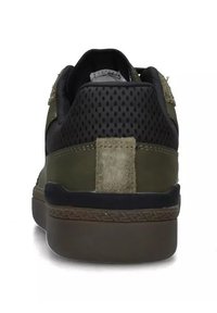 Sneaker verde con sovrapposizioni in mesh nero, dettagli in suede texturizzato e una robusta suola in gomma marrone. Presenta colletto imbottito e linguetta sul tallone.
