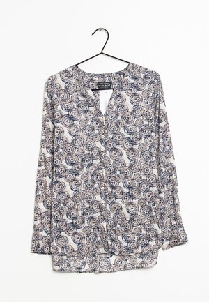 Blouse à manches longues avec un décolleté en V, présentant un motif floral bleu marine et beige, en tissu léger, avec des détails de boutons.