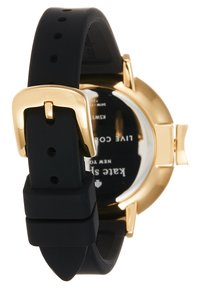 Correa de reloj de silicona negra con hebilla de metal dorado. El fondo de la caja muestra la marca. Presenta un diseño redondo y una textura suave.