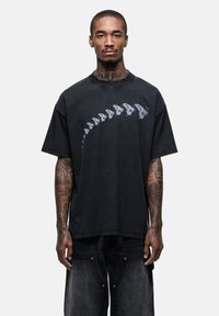 Zwarte oversized t-shirt met een skeletvlinderprint op de voorkant. Zachte textuur, ronde hals en korte mouwen.