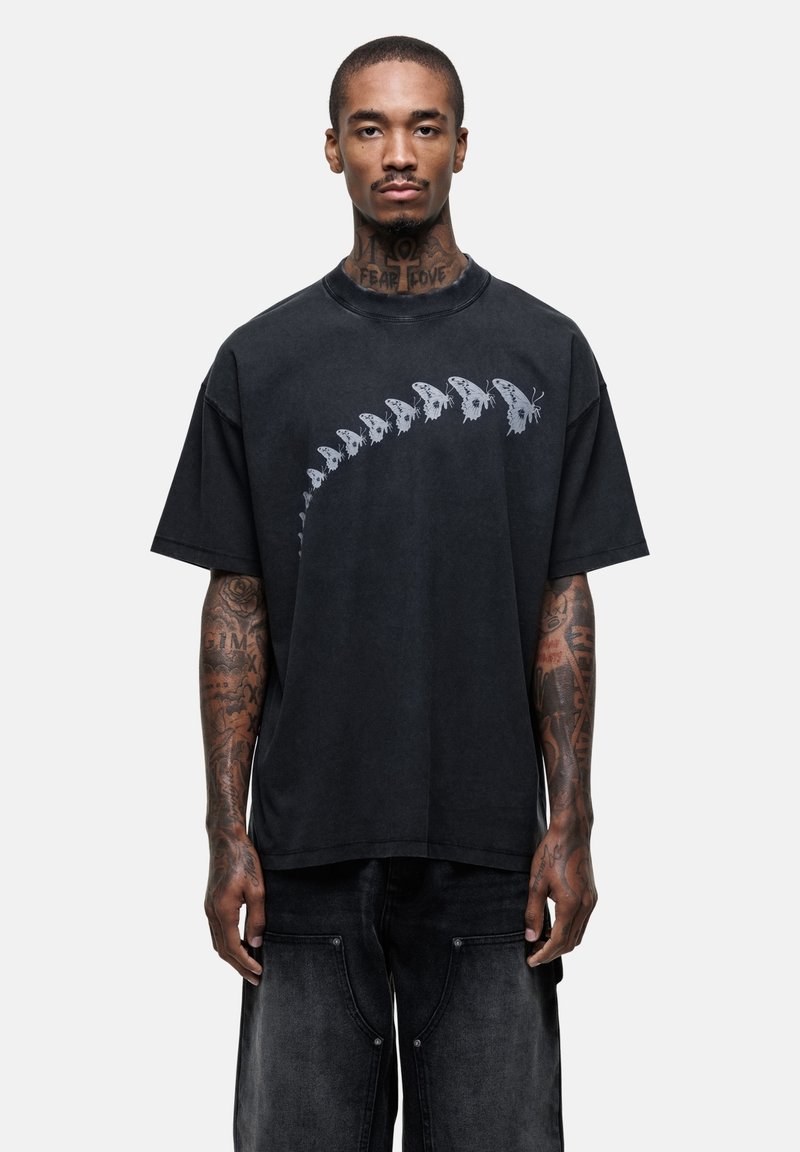 Zwarte oversized t-shirt met een skeletvlinderprint op de voorkant. Zachte textuur, ronde hals en korte mouwen.