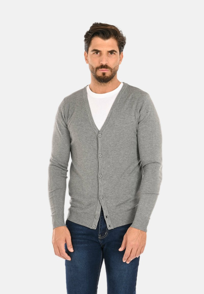 Cardigan grigio realizzato in materiali morbidi, con scollatura a V, chiusura a bottoni e polsini a coste. Abbinato a una t-shirt bianca e jeans scuri.