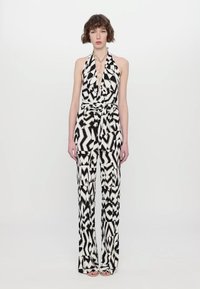Zwart-wit gestreepte jumpsuit met een halternek, een ceintuur op de taille, brede pijpen en zakken. Gladde stof met een geometrisch ontwerp.