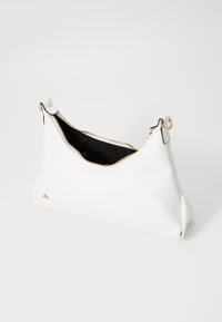 Sac en cuir blanc avec un design géométrique, fermeture éclair dorée et accents décoratifs. L'intérieur est noir, avec un espace de rangement supplémentaire à poches.